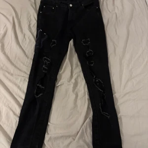 Svarta slim jeans från Amiri - Svarta slim jeans från Amiri med slitna detaljer längs benen. De har en klassisk femficksdesign och en diskret logga på baksidan.