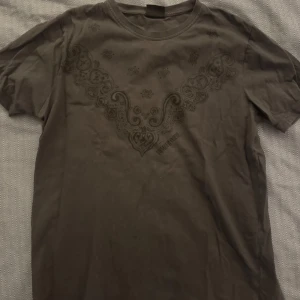 Svart t-shirt från Marlboro x Number (N)ine - Snygg svart t-shirt med ett unikt mönster på framsidan från Marlboro x Number (N)ine. Perfekt för dig som gillar stilrena och coola plagg. Storlek F, vilket kan motsvara en medium beroende på märke.