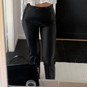 Skinnbyxor  - Snygga svarta högmidjade skinnbyxor i ett stretchigt material. De har en tight passform som framhäver figuren och ger en stilren look. Perfekta för en trendig outfit.