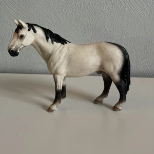 Schleich häst - Detaljerad hästfigur i vit och svart med realistiska drag. Perfekt för samlare eller som leksak för barn. Hästen har en elegant hållning och noggrant utformad man och svans.