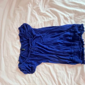 Blå topp från Tamsin - Säljer en blå topp från Tamsin med korta ärmar och elastiska detaljer vid ärmslut och nederkant. Perfekt för en avslappnad stil. Sitter som xs/s men är väldigt stretchig