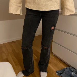 Svarta jeans från Gina tricot  - Snygga svarta jeans med slitna detaljer från G Perfect Jeans. De har en tight passform och är perfekta för en trendig look. Jeansen har en klassisk design med dragkedja och knapp framtill.