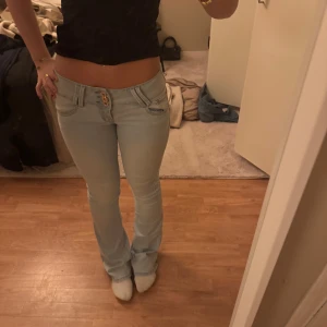 Ljusblå jeans med låg midja - Snygga ljusblå jeans med låg midja och tight passform. De har en dekorativ knapp framtill och klassisk femficksdesign. Perfekta för en avslappnad stil. Aldrig använda 👍🥹