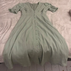 Happyholly klänning - Fin klänning i en underbar ljus grön färg, snöre som går att knyta bak eller fram, något man själv får välja hur man gillar det! Knapparna längs hela vägen går att knäppa upp🤩storlek 36/38