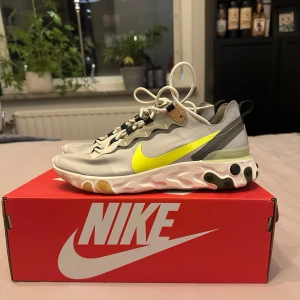 Nike React - Snygga Nike sneakers i grått med neongröna detaljer och vit sula. Skorna har snörning och en unik design med svarta och bruna accenter. Perfekta för en sportig look.