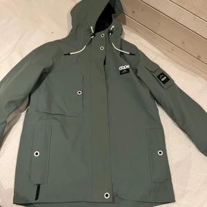 Grön jacka från Dope - Säljer en ljus grön jacka från Dope med huva och dragkedja. Jackan har flera fickor och justerbara snören vid huvan. Perfekt för utomhusaktiviteter med sin vattentäta och andningsbara design. 🏔️