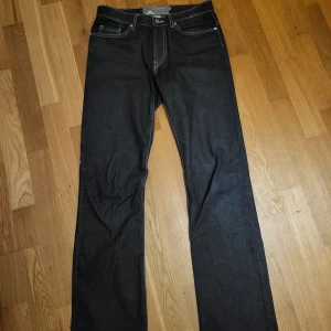 Svarta jeansbyxor från J.Lindeberg - Snygga svarta jeans från J.Lindeberg med kontrasterande sömmar. 30/34 sitter ganska slim