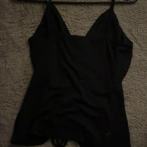 Svart linnetopp från Gina Tricot - Snygg svart linnetopp från Gina Tricot med smala axelband och rynkdetalj framtill. Perfekt för en stilren look. Toppen är i ett mjukt och bekvämt material.