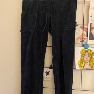 Mörkblå mjukisbyxor från Juicy Couture - Säljer ett par mörkblå lågmidjade mjukisbyxor från Juicy Couture. Byxorna har en snörning i midjan och fickor både fram och bak. Längden på benen är korta för mig som är ca 165 cm. Finns en fläck på framsidan på ena fickan, vet inte om den går bort i tvätten. Vet ej om det är äkta Juicy Couture. 