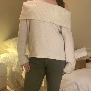 Beige stickad tröja från Gina Tricot - Mysig beige stickad tröja från Gina Tricot med en bred krage. Perfekt för kyliga dagar med sin mjuka och bekväma passform. Tröjan har långa ärmar och en avslappnad stil. Bara använd ca 5 ggr 