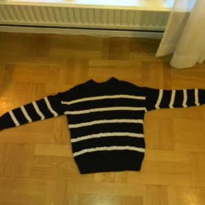 Svart och vit randig tröja - Säljer en svart stickad tröja med vita ränder. Tröjan har långa ärmar och en klassisk rund hals. Perfekt för en stilren look. 🖤🤍