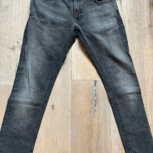 Svarta jeans från Nudie Jeans - Snygga svarta jeans från Nudie Jeans med en klassisk femficksdesign. De har en diskret tvätt för en cool look och är perfekta för en avslappnad stil. Märkesloggan syns på baksidan av midjan. Storlek 32/30