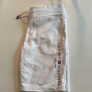 Vita shorts från Tommy Hilfiger - Snygga vita shorts från Tommy Hilfiger med ribbad midja och snörning. De har en logga på benet och en bakficka. Perfekta för en avslappnad stil. Inköpta för 700 säljes för 150