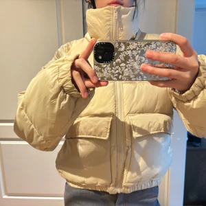 Beige pufferjacka - Säljer en snygg beige pufferjacka med dragkedja och hög krage. Jackan har långa ärmar och två stora fickor framtill. Perfekt för kyliga dagar när du vill hålla dig varm och stilren. 🧥✨