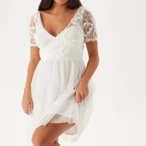 Vit spetsklänning -  Vit klänning från bubbelroom med spetsdetaljer och korta ärmar. Aldrig använd och lapp finns kvar. Nypris 899