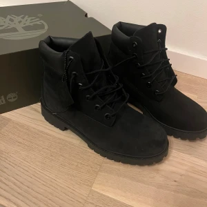 Svarta boots från Timberland - Snygga svarta boots från Timberland med robust sula och klassisk snörning. Perfekta för höst och vinter med sin slitstarka design. Dessa boots har en stilren look som passar till många olika outfits.