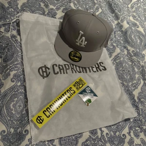 Grå keps från CapHunters - Snygg grå keps från CapHunters med broderad logotyp framtill. Kepsen har en klassisk design och är perfekt för vardagsbruk. Den är tillverkad i ett slitstarkt material och har en bekväm passform den har aldrig varit använd för att den är förstor bara testad.