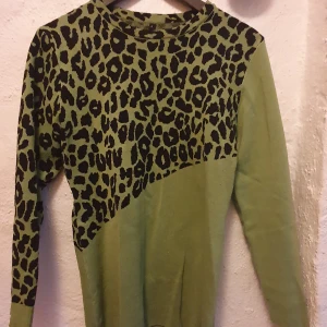 Grön leopardmönstrad tröja - Snygg grön tröja med leopardmönster upptill. Tröjan har långa ärmar och en rund halsringning. Perfekt för att ge en djärv touch till din outfit.