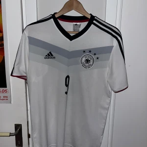 Retro fotbollströja - Tja! Säljer nu denna Tysklands fotbollströja från 2013/14. Med André shurrle på ryggen. Tyvärr har lite av numret där bak lossnat därav billiga priset. Annars är den i toppskick för att vara så gammal. (Inga fläckar)