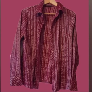 Super läcker Vinröd randig skjorta Large - Super fin skick och vacker skjorta . Det som gör "it" med skjortan/blusen är  de randiga detaljerna.  Men det står storlek 46 på skjortan så känns det mer som en 42/44 mer. 