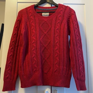 Röd stickad tröja från Etivel - Säljer en snygg röd stickad tröja från Etirel. Den har ett klassiskt flätmönster och är perfekt för kyliga dagar. Tröjan är i storlek M och har långa ärmar med ribbade muddar. Supermysig och stilren för både höst och vinter!