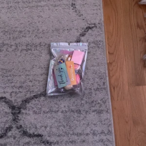 Sminkset i holografisk påse - Ett sminkset i en snygg holografisk påse. Innehåller flera olika produkter, inklusive en rosa förpackning och en liten flaska. Perfekt för att testa nya produkter eller ha med på resan!