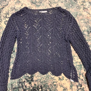 Blå stickad tröja från Zara - Säljer en superfin blå stickad tröja från Zara. Den har ett snyggt hålmönster och är perfekt för lager-på-lager-stil. Tröjan är långärmad och har en lite vågig kant nertill. Perfekt för både höst och vår!