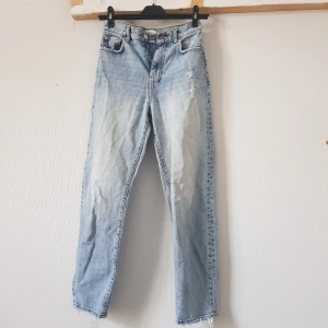 Ljusblå jeans från Gina Tricot - Säljer ett par ljusblå jeans från Gina Tricot i storlek 34. De har en klassisk straight fit och är tillverkade i denim. Jeansen har slitning på framsidan och längst ner.