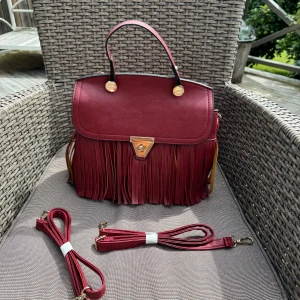 Ny Röd väska. Fungerar som ryggsäck.  - Ny röd väska med fransar och gulddetaljer. Dragkedja på baksidan och flera fack inuti för bra organisering. Väskan kommer med justerbar axelrem så du kan bära den som du vill. Även som ryggsäck. Ej skinn. Hämtas på Hägerstensåsen el ök. 