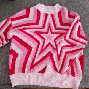 Rosa och röd stickad tröja med stjärnmönster - Stickad tröja i rosa och rött med ett stjärnmönster.Tröjan har långa ärmar och ribbade muddar vid ärmslut och nederkant. Den är både bekväm och perfekt för höst och vinter ❤️🩷 obs betalning bara igenom swish 