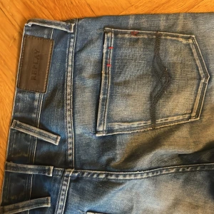 Replays Anbass 31 - Blå replay Anbass med slitningar och coola röda detaljer. Storlek 31 (slim fit jeans)