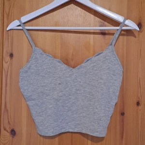 Grå ärmlös linnetopp - Säljer en enkel och stilren grå linnetopp. Den är ärmlös med smala axelband och har en bekväm passform. Perfekt för sommardagar eller som ett basplagg i garderoben.