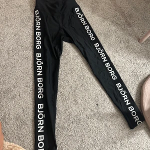 Svarta leggings från Björn Borg - Snygga svarta leggings från Björn Borg med logotyp längs benen. Perfekta för träning eller en avslappnad dag. De är högmidjade och har en tight passform som ger en bekväm känsla. De är i storlek 38 men fungerar även som s då de är lite små i storlek
