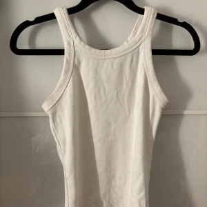 Vitt linne - Fint vitt ribbat linne med breda axelband från H&M. Bra basplagg, det kommer inte till användning längre. 