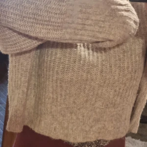 Beige stickad tröja - Mysig beige stickad tröja med ribbad struktur. Perfekt för kyliga dagar med sin bekväma passform och långa ärmar. En stilren och enkel design som passar till det mesta.