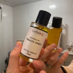 Parfym  - Curiosa Eau de Parfum inspirerad av Tobacco Vanile. Flaskan rymmer 50 ml och har en elegant design med svart kork och en stilren etikett. Perfekt för den som söker en doft med inslag av tobak och vanilj.