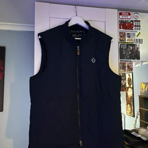 Marinblå quiltad väst från Morris - Säljer en stilren mörkblå quiltad väst från Morris med dragkedja och broderad detalj på bröstet. Perfekt för lager-på-lager under kyliga dagar. Västen har en klassisk design och är tillverkad med högkvalitativa material. 10/10 skick även använd bara två gånger, annars hängd på en galge på rummet. Nypris 1499kr Fynda medans ni kan!