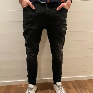 Nudie Jeans - Snygga svarta jeans från Nudie Jeans med en tight passform. De har en klassisk design med fem fickor och slitningar för en trendig look. Perfekta för en stilren outfit. Dem är i storlek 28/30 och modellen är 180 cm lång. Nypris på dessa godingar ligger på ca 1500kr. Hör av er vid funderingar eller frågor! Pris kan diskuteras vid snabb affär🙌