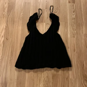 Svart stickad linne i storlek xxs-xs från Only har klippt bort lappen på den som du ser på bilden - Snygg svart stickad linne med smala axelband och v-ringning. Perfekt för lager-på-lager eller sommarens varma dagar. Den har en ribbad struktur som ger en fin detalj till outfiten.