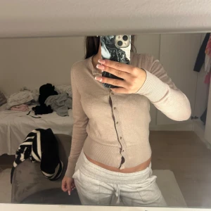 Beige kofta från Holly & White - Säljer en stilren beige kofta från Holly & White by Lindex. Koftan har långa ärmar och knappar framtill, perfekt för en avslappnad look. Passar bra till både jeans och kjol.