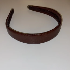 Brunt diadem - Brunt diadem i skinnimitation. Passar bra till både vardag och speciella tillfällen. Lite slitage förekommer (se bild 3) därav lågt pris.