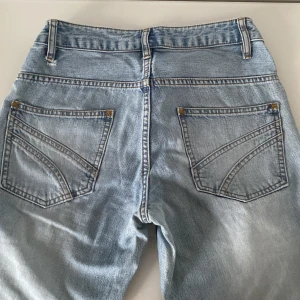 Ljusblå jeans - Snygga ljusblå jeans med klassisk femficksdesign och knappgylf. Perfekta för en avslappnad stil. De har en rak passform och är tillverkade i ett slitstarkt denimtyg.