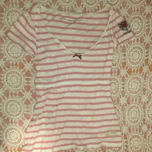 Randig topp från Odd Molly - Säljer en söt randig topp från Odd Molly i rosa och vit. Toppen har en v-ringad design med en rosett.