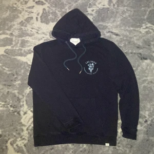 Mörk Blå Hoodie från Les Deux - Snygg blå hoodie från Les Deux med tryck på bröstet. Hoodien är i storlek Large men passar som Medium/Small.  