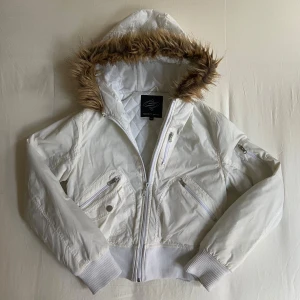 Vit jacka med fuskpäls från Sister's Point - Snygg vit jacka från Sister's Point med fuskpäls på huvan, lite kortare. Dragkedja framtill och flera fickor. Är lite gråaktig på ärmarna men annars super bra skick. 