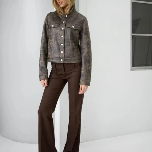 NELLY skinnjacka  - JACKA MED ETIKETT! Snygg grå skinnjacka med en vintage-look och knappar framtill. Jackan har en klassisk krage och två bröstfickor med lock. Perfekt för en cool och avslappnad stil.