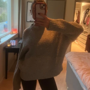 Grå stickad tröja - Mysig grå stickad tröja med en loose passform. Perfekt för kyliga dagar med långa ärmar och ribbade kanter. Enkelt att matcha med olika outfits.