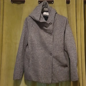Grå jacka från ONLY - Säljer en stilren grå jacka från ONLY med luva och knappar framtill. Perfekt för kyliga dagar med sin långa ärm och mjuka material. Passar bra till både vardag och mer uppklädda tillfällen. Passar L och XL. 