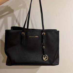 Svart axelväska från Michael Kors - Snygg svart axelväska från Michael Kors med gulddetaljer och logotyp. Väskan har en rymlig insida med dragkedja och flera fack för enkel organisering. Perfekt för att bära med sig allt man behöver under dagen. Inte sliten alls då den bara inte kommit till användning helt enkelt. 💗Äkta såklart. 💖Frakt via Instabox/ PostNord.                       NYPRIS : 2800kr 