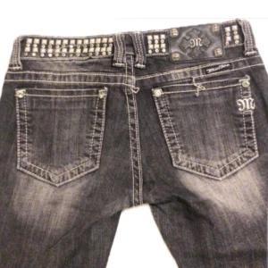 miss me jeans - Snygga svarta/gråa miss me jeans med coola nitar längs midjan och fickorna. De är bootcut och lågmidjade💕 skicket/ defekter syns i bilderna storlek 28, mått: midja- 38/39 cm innerben- 78 de är utsydda till bootcut 